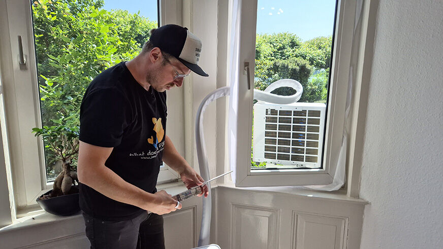 Midea PortaSplit Außengerät auf einem Balkon befestigt am Fensterrahmen